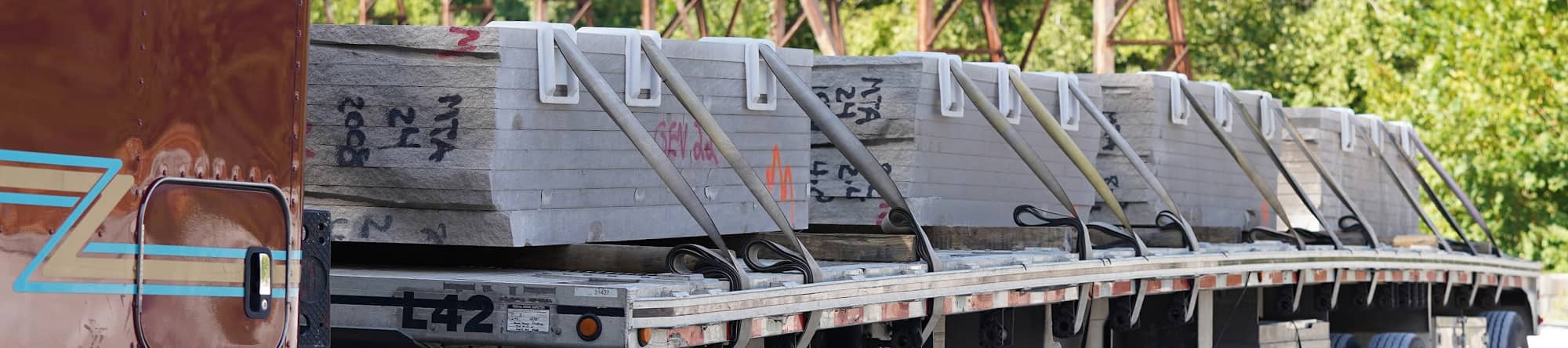 A truck loaded with securely strapped Indiana Limestone slabs, ready for delivery, showcasing the high-quality craftsmanship and reliability of B.G. Hoadley Quarries.