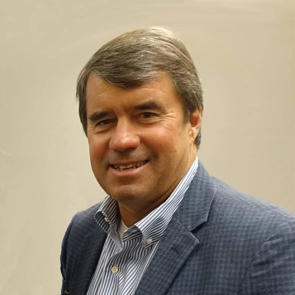 Portrait of David Ross Fell, former president of B.G. Hoadley Quarries Inc., wearing a blue checkered blazer and striped shirt, smiling against a beige background.