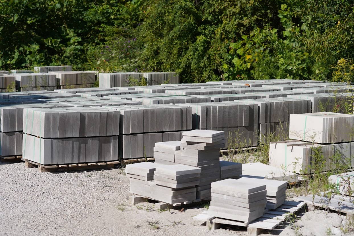Stacks of rectangular limestone blocks and slabs on pallets at B.G. Hoadley Quarries, arranged neatly in an outdoor storage yard with gravel ground.