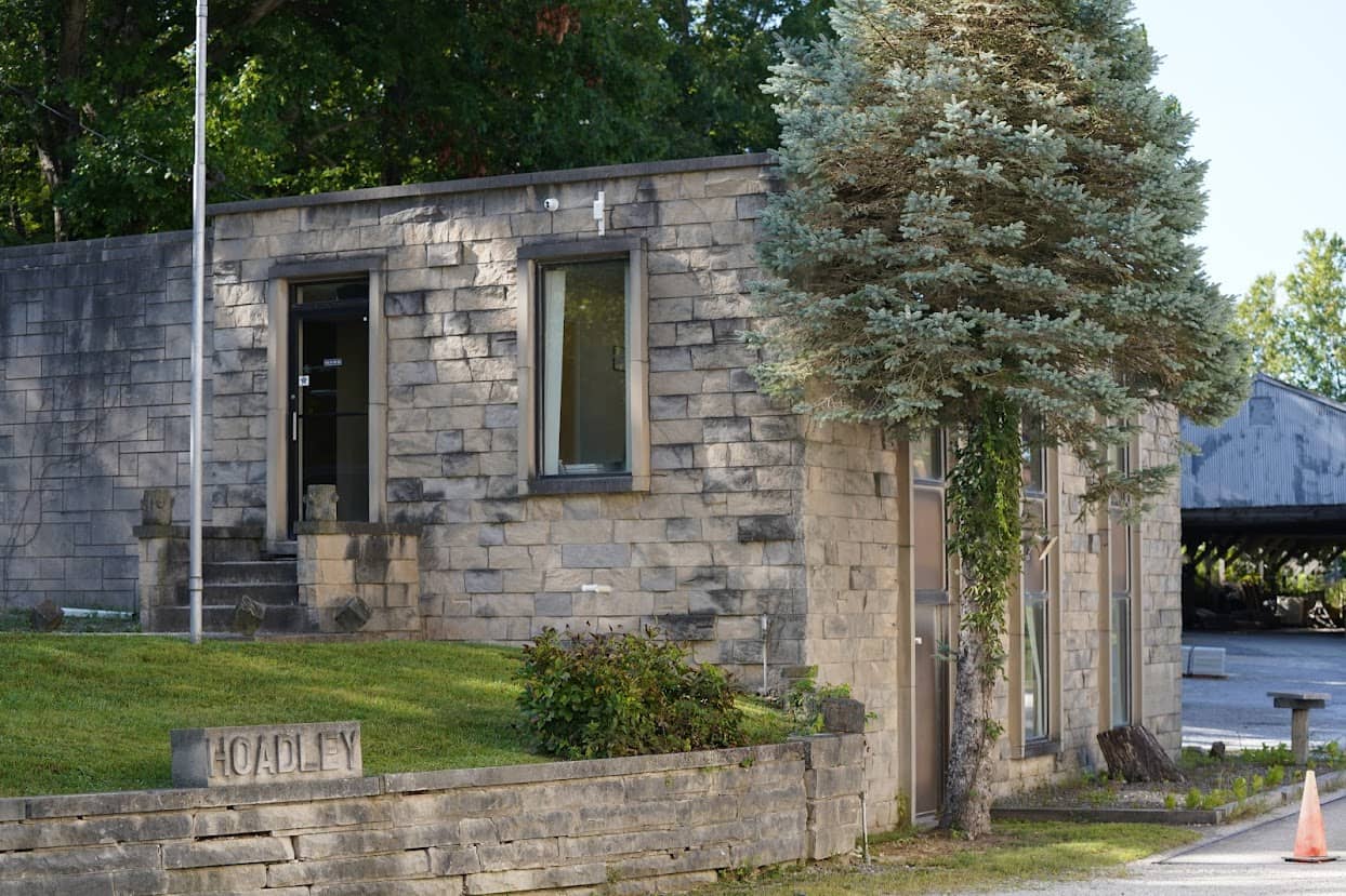 Front view of the B.G. Hoadley Quarries office building with limestone exterior walls, a manicured lawn, and a carved stone labeled "HOADLEY".