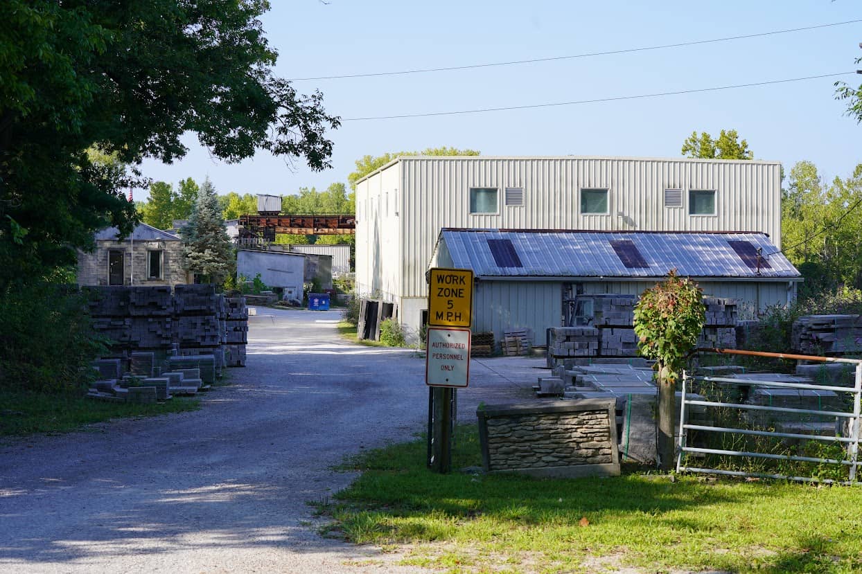 Exterior view of B.G. Hoadley Quarries yard with stacked stone, metal buildings, and signage indicating a work zone and restricted access.